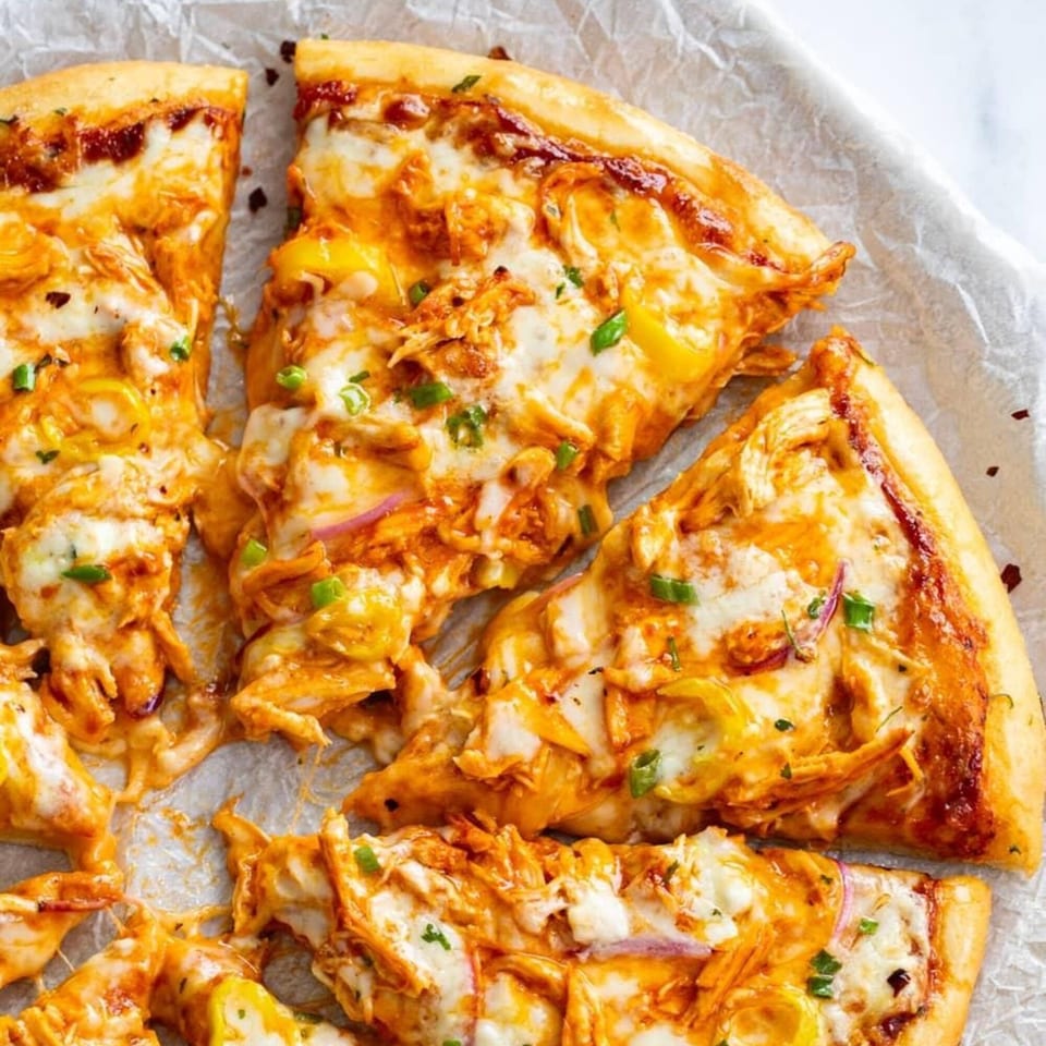 Close-up of several slices of Roma Pizza & Pasta's chicken pizza with melted cheese and green onions.